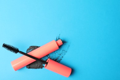 Photo of Mascara and smear on light blue background, flat lay with space for text. Makeup product