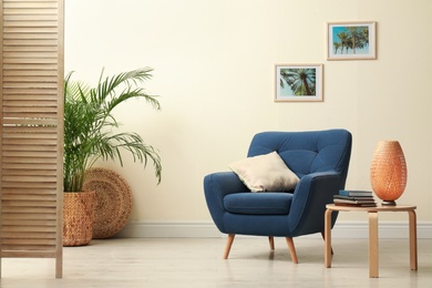 Photo of Stylish room interior with comfortable furniture and plant near beige wall