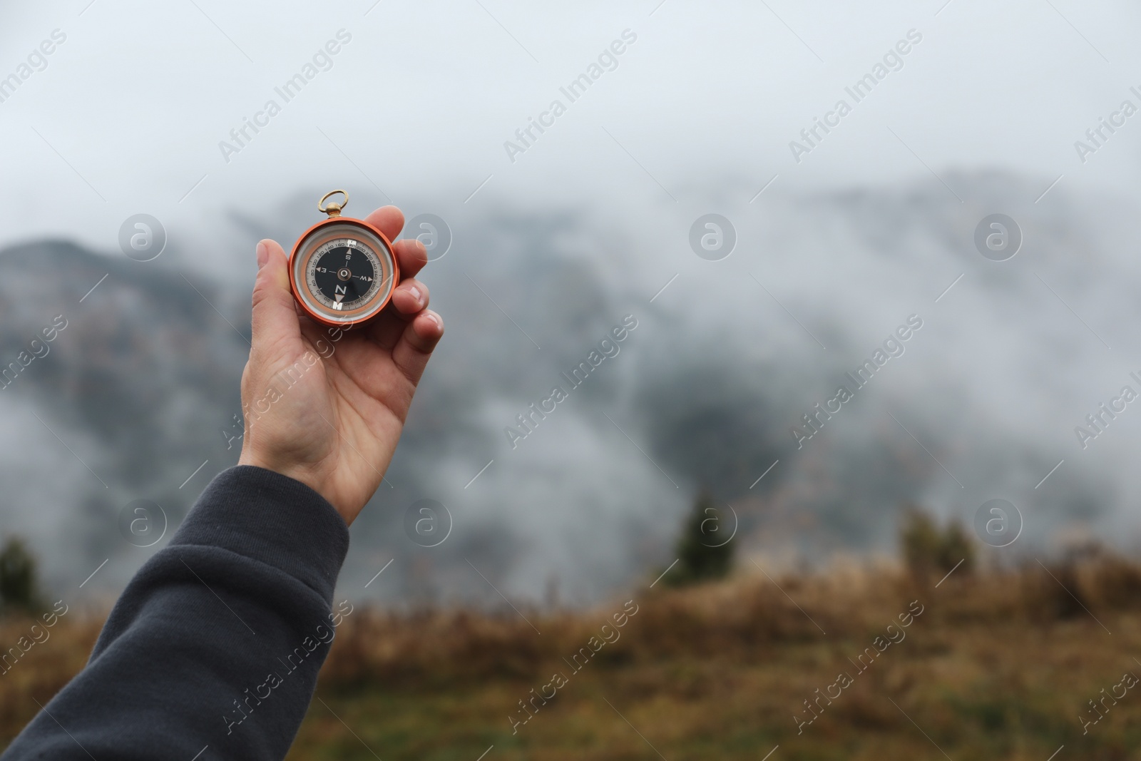 Photo of Woman using compass during journey in mountains, closeup. Space for text