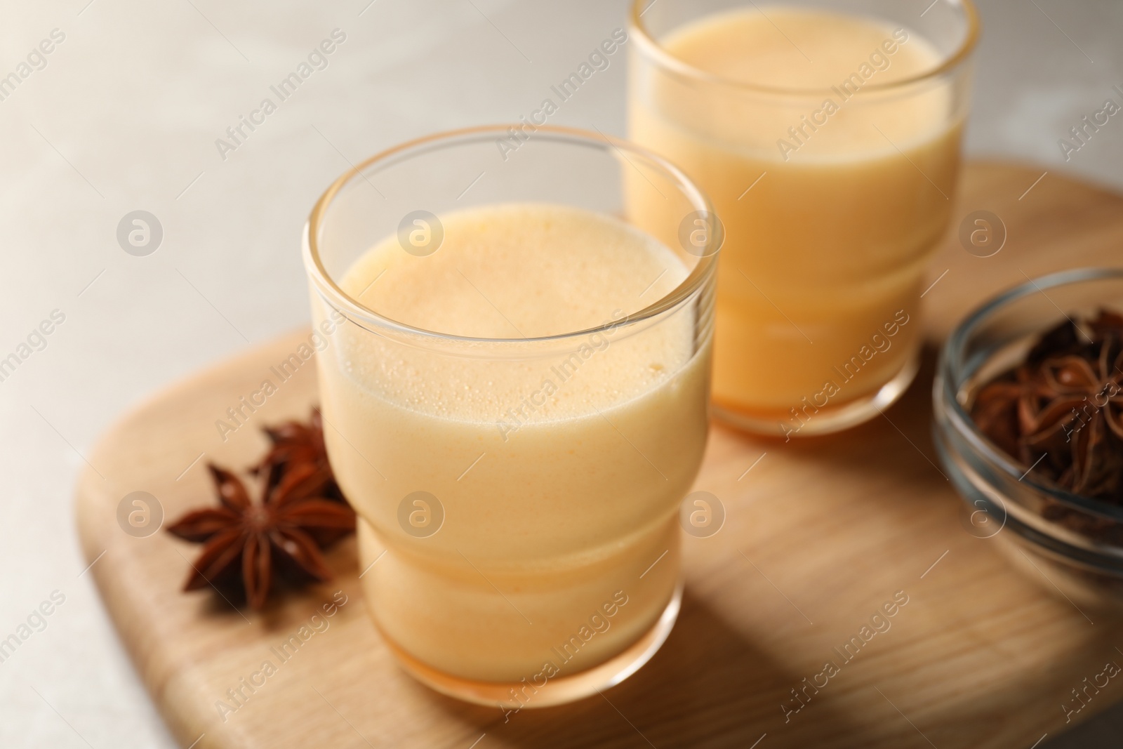 Photo of Glasses of delicious eggnog with anise on grey marble table, closeup