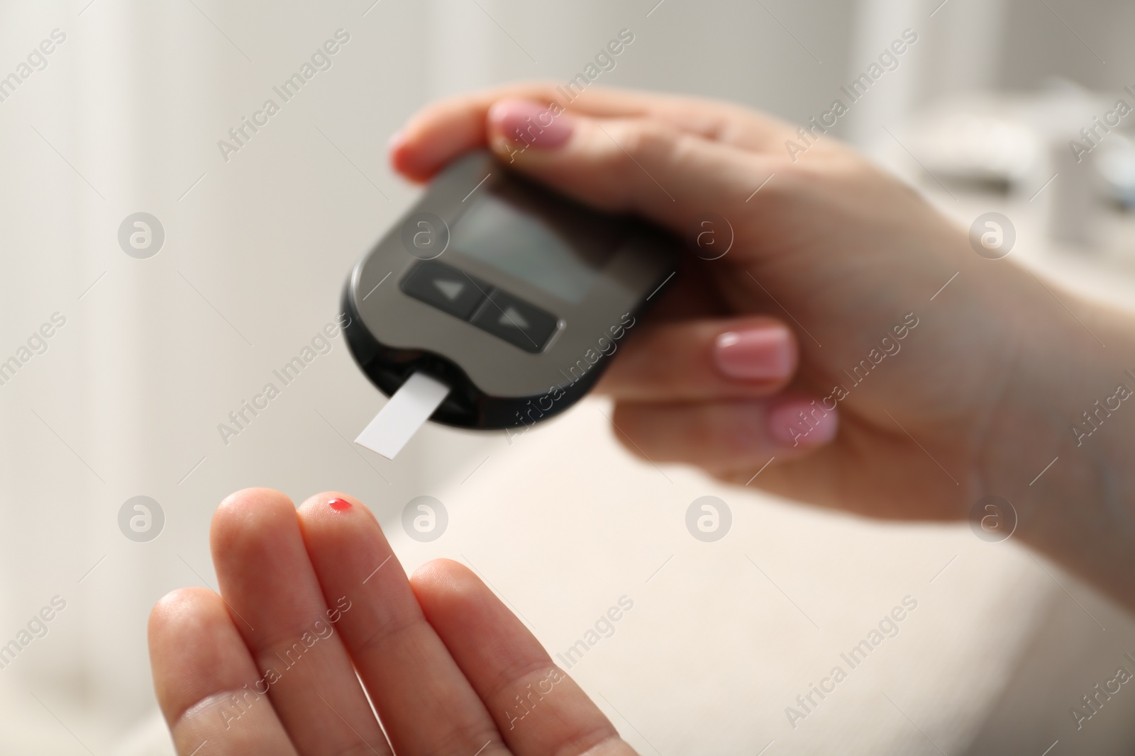 Photo of Diabetes. Woman checking blood sugar level with glucometer at home, closeup