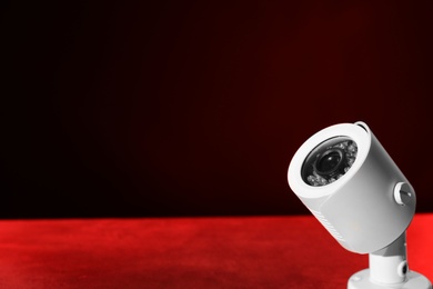 Photo of Modern security CCTV camera on table against dark background