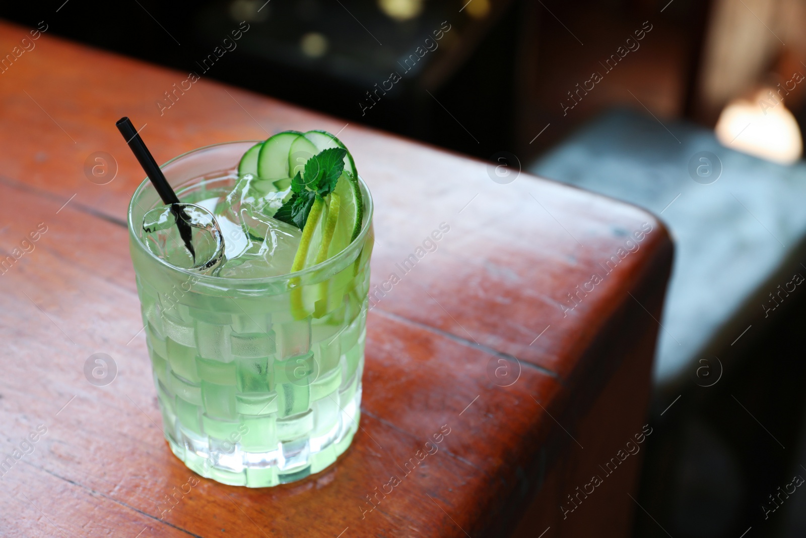 Photo of Glass of delicious cocktail with ice on table in bar