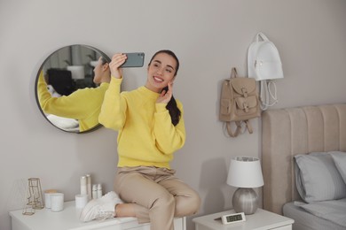 Young woman taking selfie at home in morning