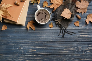 Photo of Flat lay composition with cup of hot drink and autumn leaves on blue wooden table, space for text. Cozy atmosphere