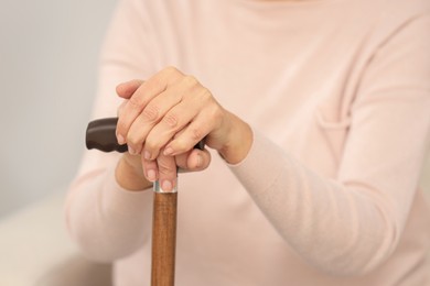 Photo of Mature woman with walking cane on blurred background, closeup