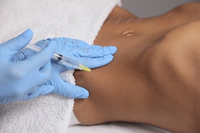 Photo of Young woman getting belly injection in salon, closeup
