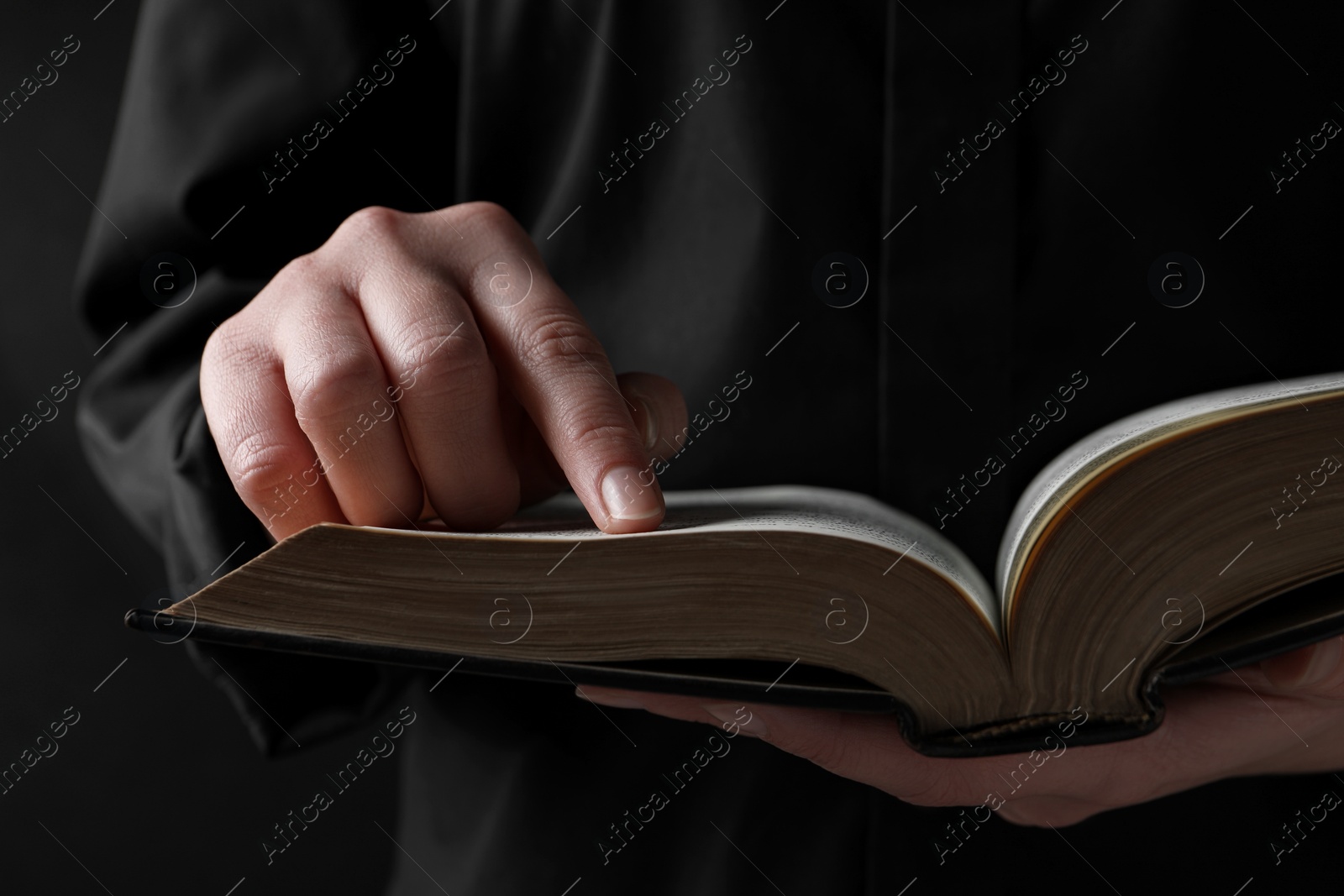 Photo of Woman reading holy Bible on black background, closeup