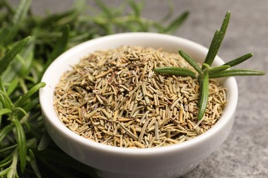 Dry and fresh rosemary in bowl on table, closeup