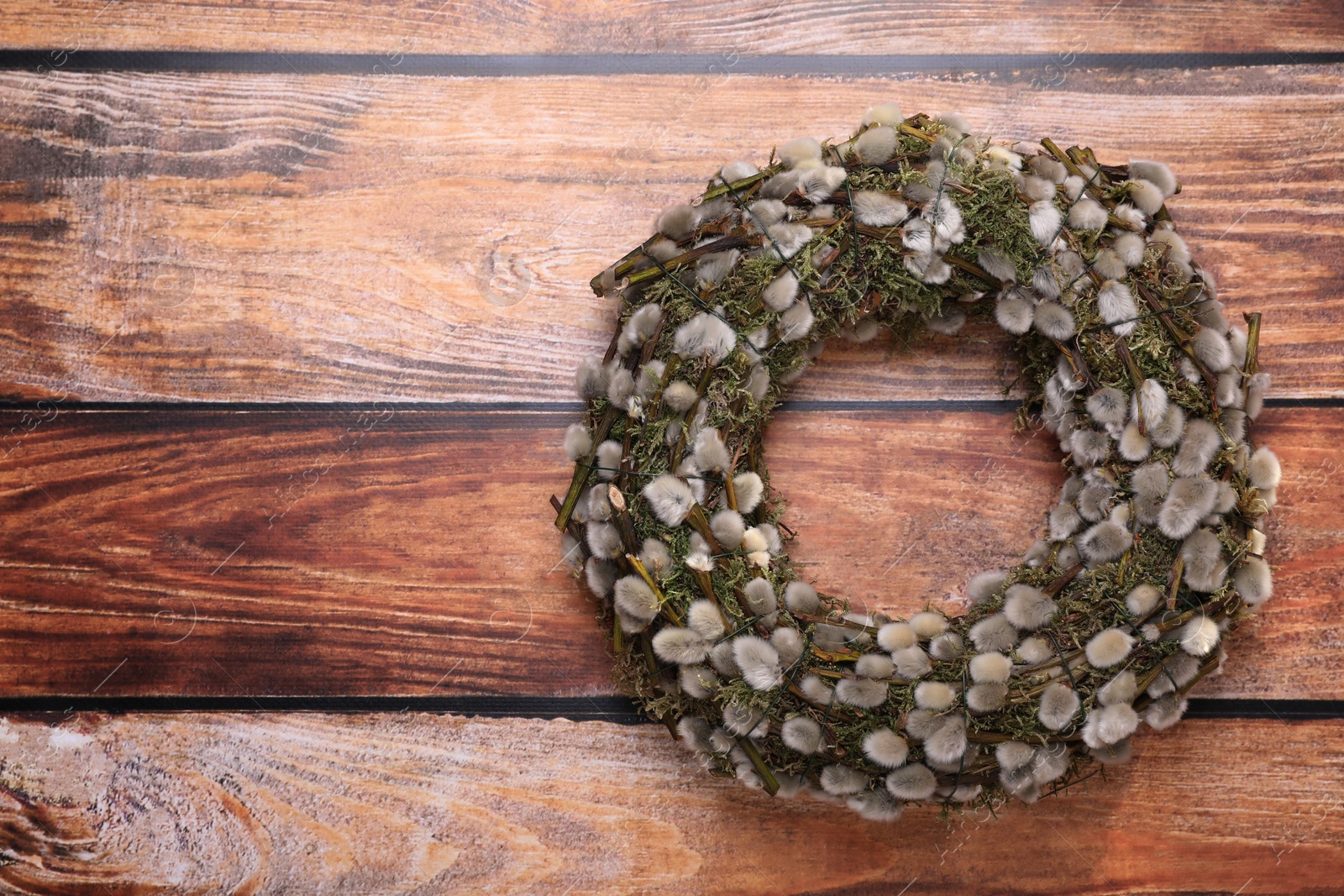 Photo of Wreath made of beautiful willow flowers on wooden table, top view. Space for text
