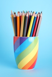 Photo of Colorful pencils in cup on light blue background