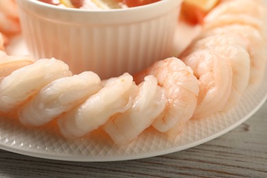 Photo of Tasty boiled shrimps with cocktail sauce on white wooden table, closeup