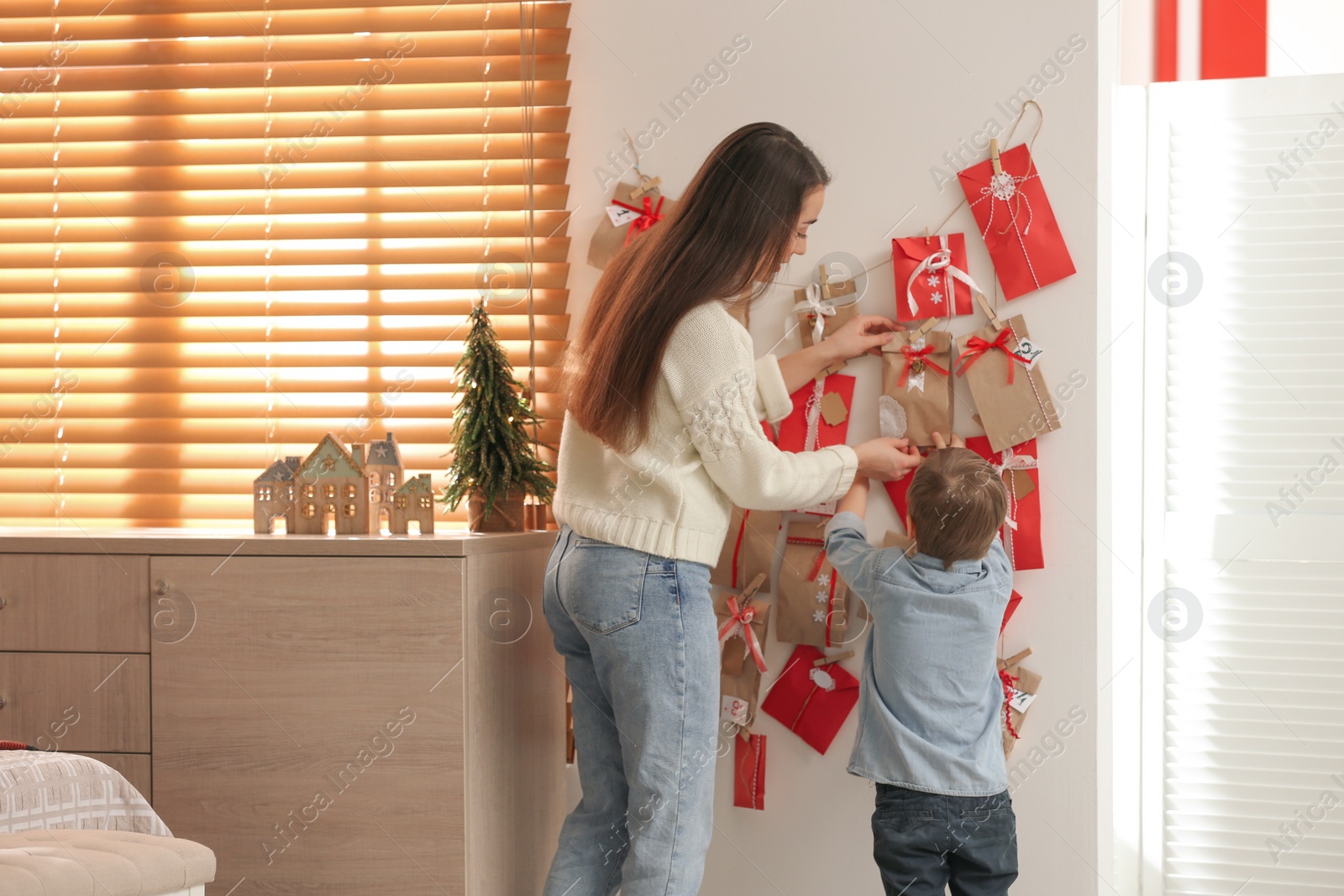 Photo of Mother and son taking gift from Advent calendar at home, back view. Christmas tradition