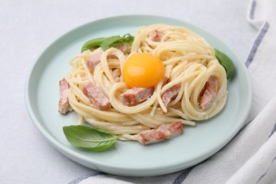 Photo of Delicious pasta Carbonara with egg yolk on white table, closeup