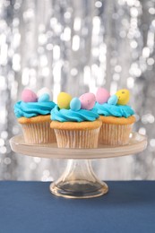 Photo of Tasty decorated Easter cupcakes on blue table, closeup