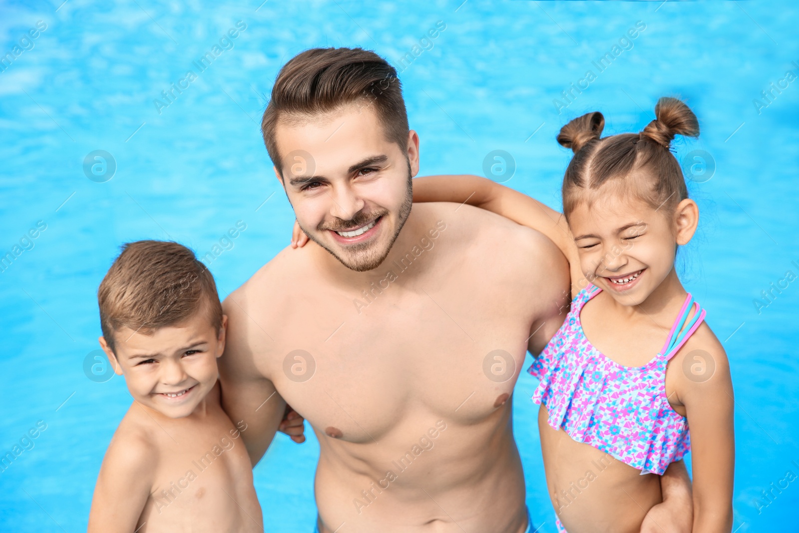 Photo of Young father with little children in swimming pool on sunny day