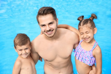 Young father with little children in swimming pool on sunny day