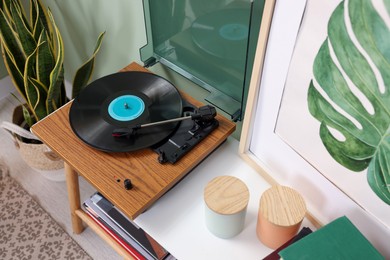 Photo of Stylish turntable with vinyl record on console table in cozy room, above view