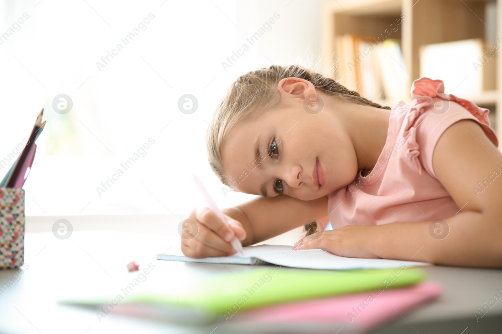 Photo of Cute little child doing assignment at desk in classroom. Elementary school