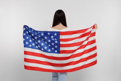 Photo of 4th of July - Independence Day of USA. Girl with American flag on white background, back view