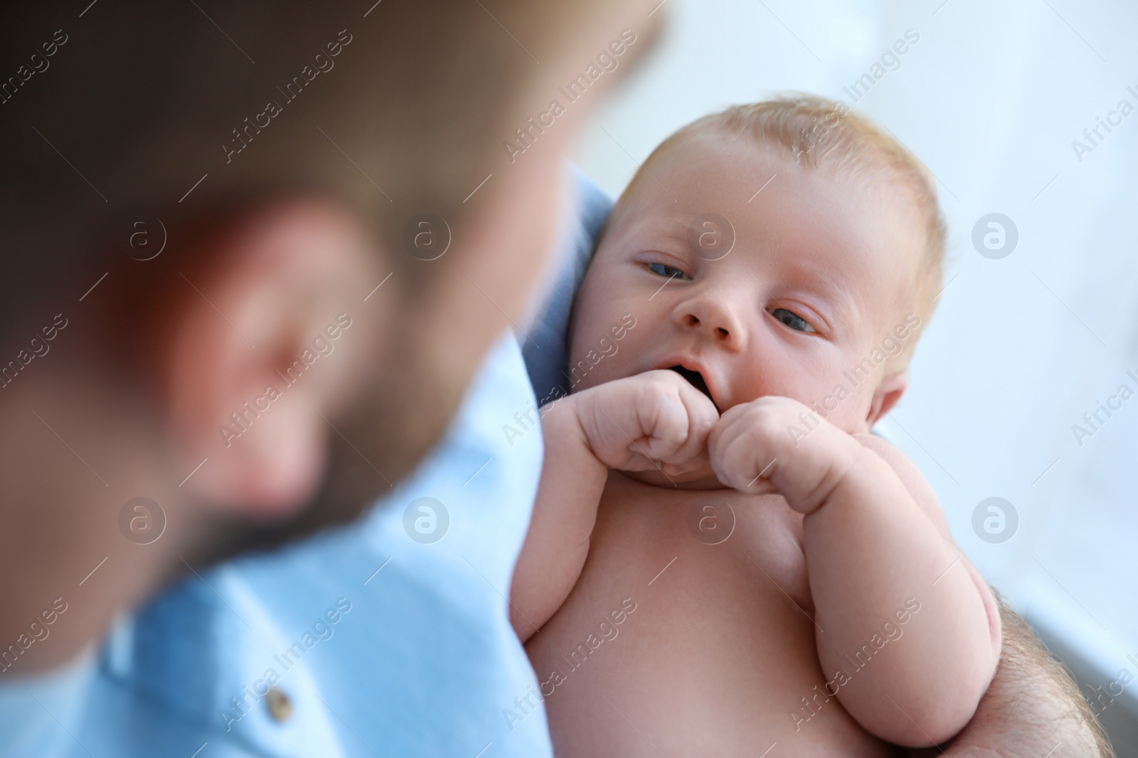Photo of Father holding his cute newborn baby at home, closeup