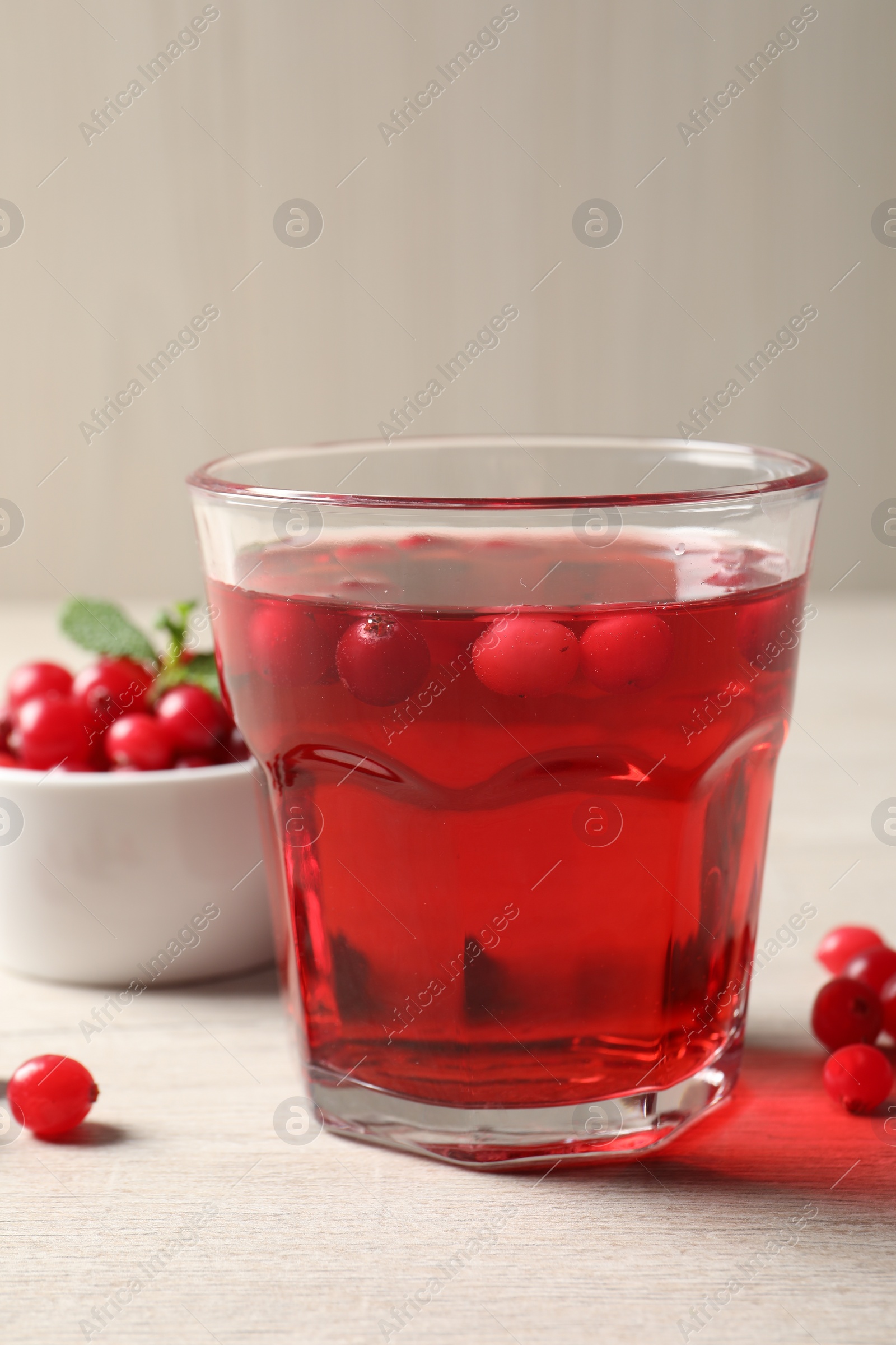 Photo of Tasty refreshing cranberry juice and fresh berries on light wooden table