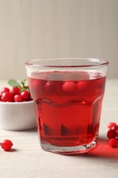 Photo of Tasty refreshing cranberry juice and fresh berries on light wooden table