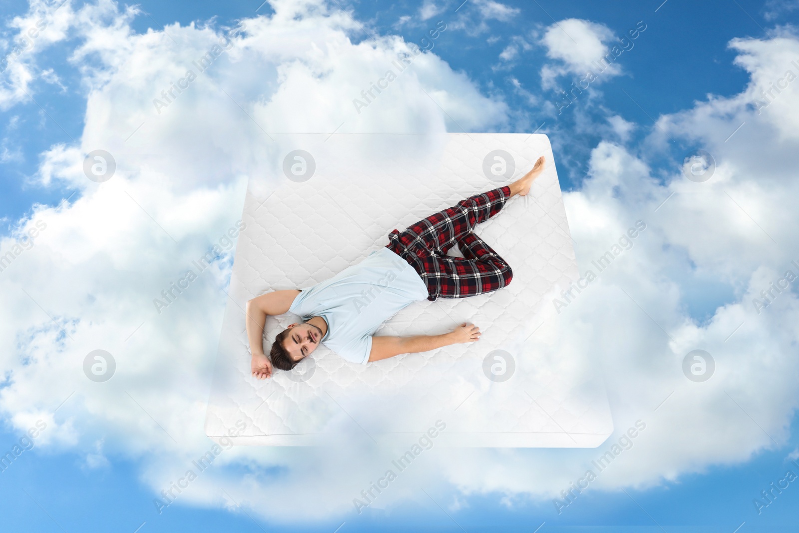 Image of Young man sleeping on mattress in clouds, above view