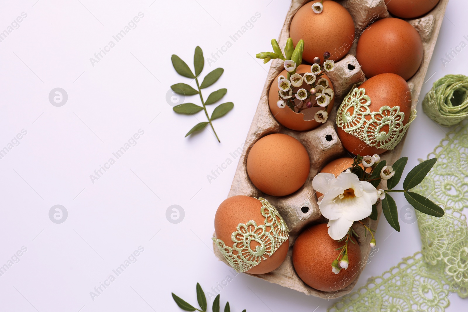 Photo of Flat lay composition with Easter eggs, twigs and lace ribbon on white background. Space for text
