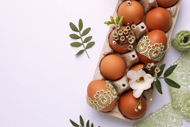 Flat lay composition with Easter eggs, twigs and lace ribbon on white background. Space for text