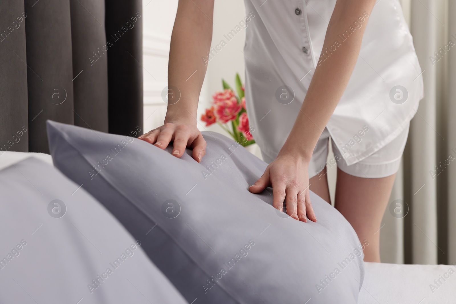 Photo of Young woman making bed in room, closeup