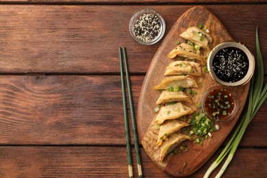 Delicious gyoza (asian dumplings) served on wooden table, flat lay. Space for text