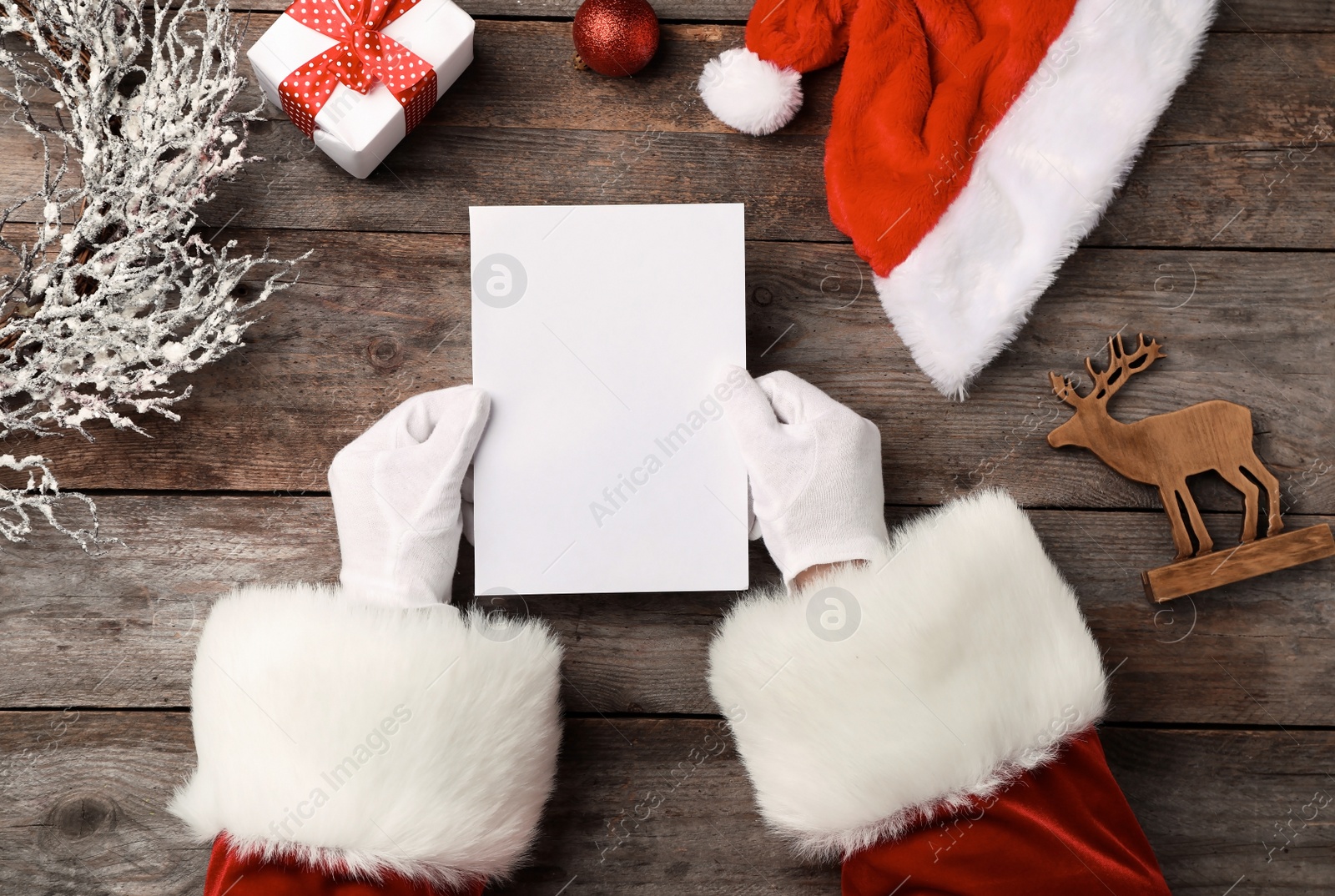 Photo of Santa Claus reading letter from child at table, top view. Christmas celebration