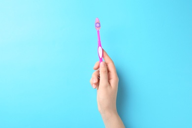 Photo of Woman holding manual toothbrush against color background