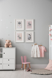 Photo of Stylish baby room interior with chest of drawers and cute pictures on wall