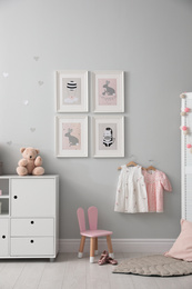 Stylish baby room interior with chest of drawers and cute pictures on wall