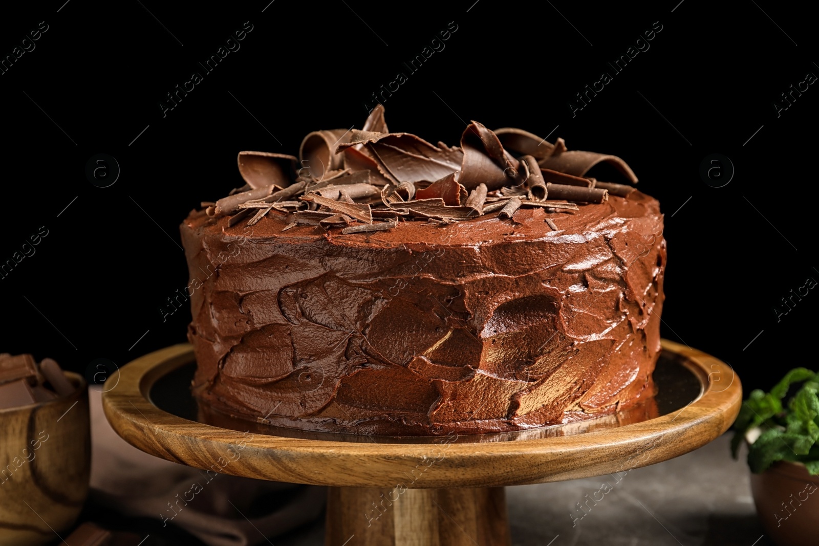 Photo of Stand with tasty homemade chocolate cake on black background