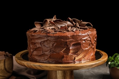 Photo of Stand with tasty homemade chocolate cake on black background