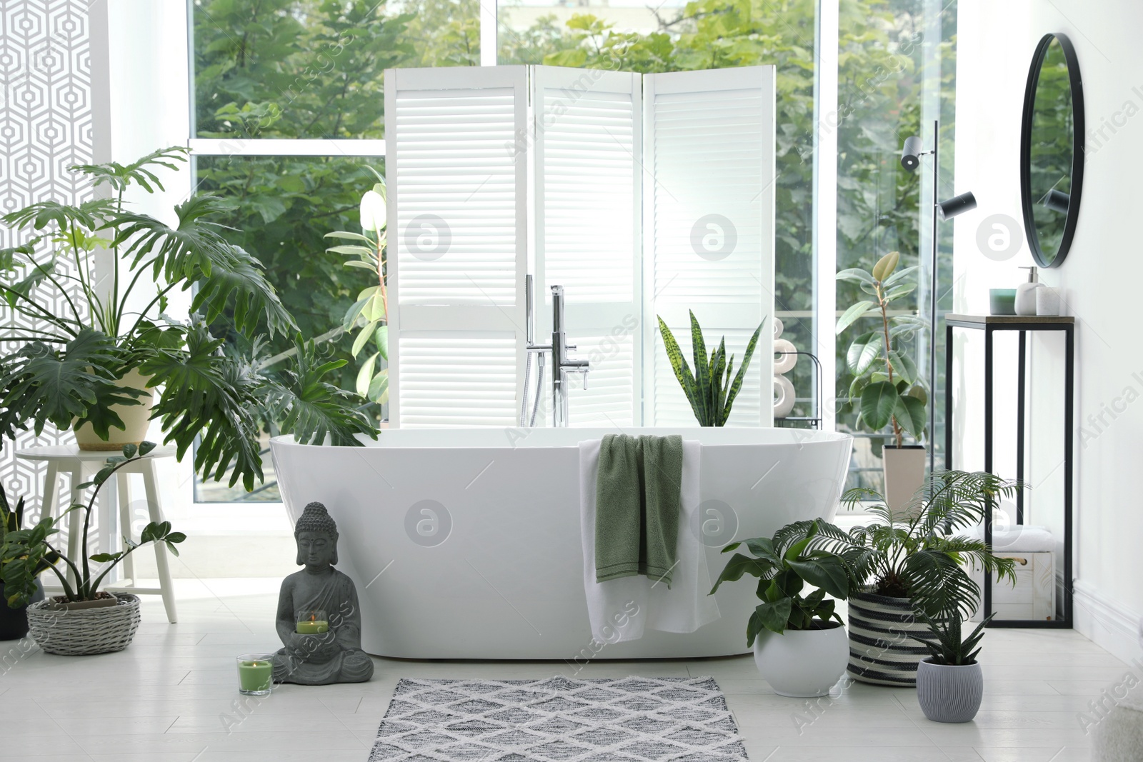 Photo of Stylish bathroom interior with modern tub, window and beautiful houseplants. Home design