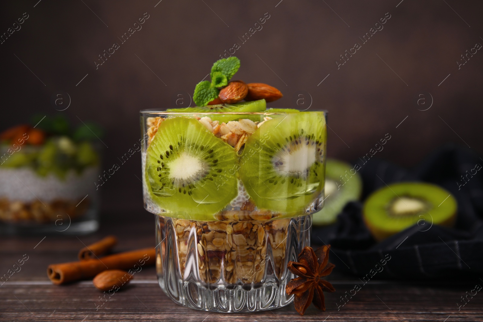 Photo of Delicious dessert with kiwi muesli and almonds on wooden table, closeup