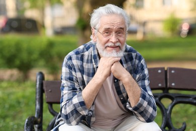 Portrait of happy grandpa with glasses on bench in park