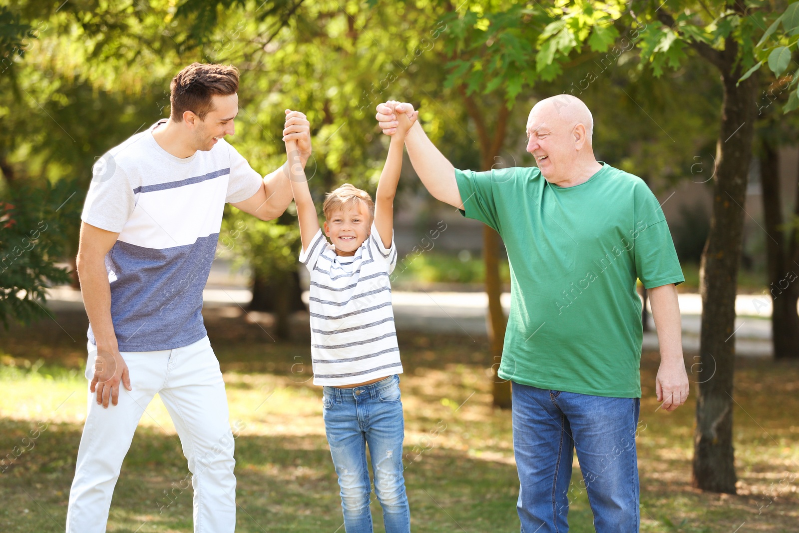 Photo of Man with son and elderly father in park on sunny day