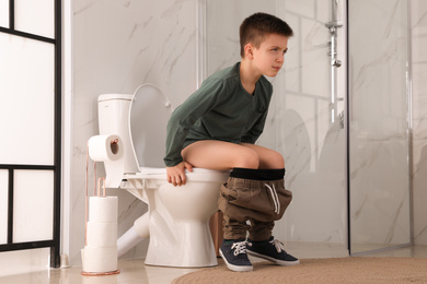 Boy suffering from hemorrhoid on toilet bowl in rest room