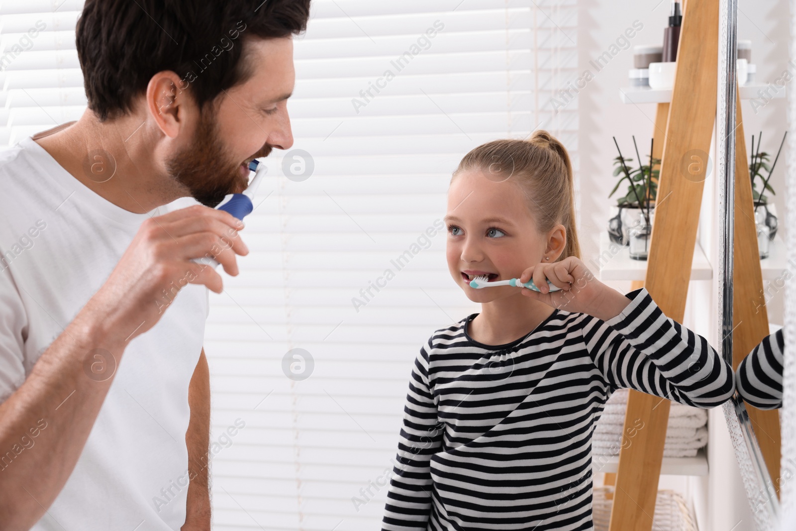 Photo of Father and his daughter brushing teeth together in bathroom