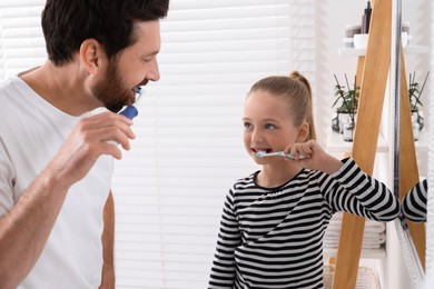 Father and his daughter brushing teeth together in bathroom