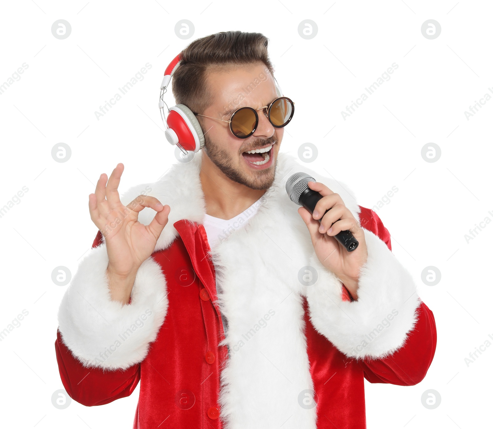 Photo of Young man in Santa costume singing into microphone on white background. Christmas music