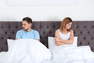 Photo of Couple with relationship problems ignoring each other in bedroom