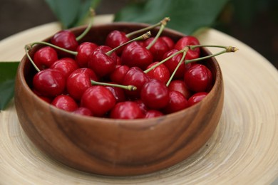 Photo of Tasty ripe red cherries in wooden bowl outdoors