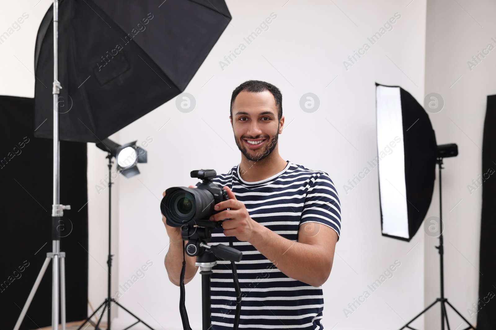 Photo of Young professional photographer with camera in modern photo studio