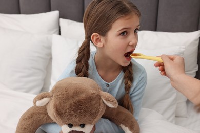 Photo of Mother giving cough syrup to her daughter at home